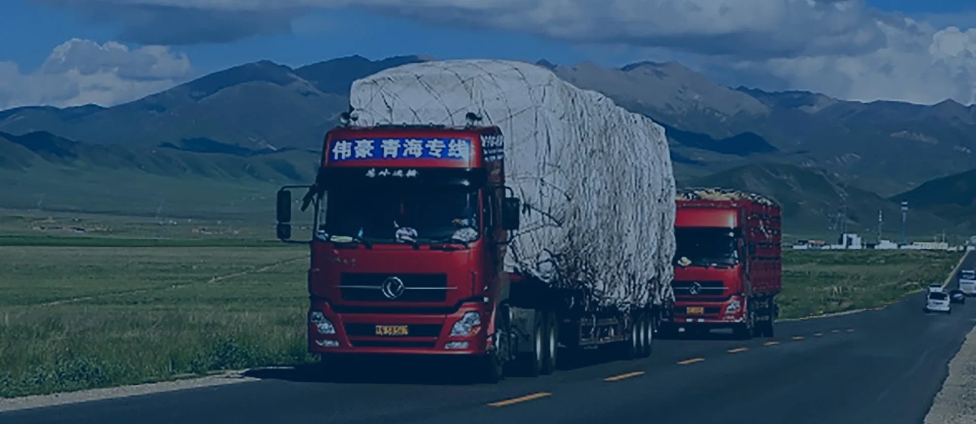 heavy-duty tractor tow truck Heavy-duty commercial trucks transporting covered bulk cargo on a scenic plateau road, supporting efficient long-distance logistics and inter-regional freight operations.